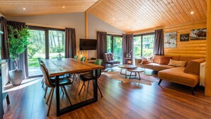 A spacious room with a wooden ceiling, a large dining table, a sofa, and a TV. - De Wiltzangh - Esborg Lodge Hottub | 6p (Ruinen)