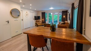 A modern dining area with a wooden table, orange chairs, and a potted plant. - De Wiltzangh - Houtenborg Lodge | 4p (Ruinen)