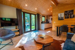A modern log cabin interior with a TV, seating, a dining area, and a kitchen. - De Wiltzangh - Sterrenborg Lodge | 4p (Ruinen)