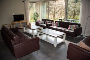Ein Wohnzimmer mit Ledersofas, einem Couchtisch und einem Fernseher auf einem Holzgestell.