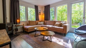 Ein gemütliches Wohnzimmer mit einer Couch, einem Couchtisch, einem Kamin und großen Fenstern.