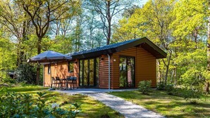 Eine Blockhütte mit einer Terrasse, einem Tisch und Stühlen.