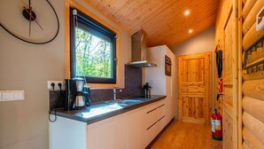 Eine kleine Küche mit Fenster, Holzboden und Feuerlöscher.