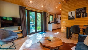 Ein modernes Blockhaus-Interieur mit Fernseher, Sitzgelegenheiten, Essbereich und Küche.