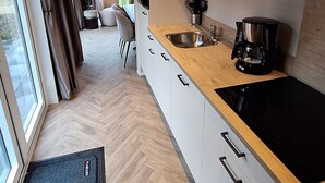 Una cocina moderna con estufa negra, armarios blancos y encimera de madera.