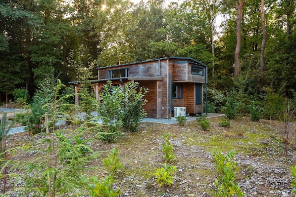 Ein modernes, zweistöckiges Haus mit Holzfassade, umgeben von dichtem Wald.