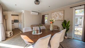 Een moderne eetruimte met een houten tafel, beige stoelen en een vaas met bloemen.