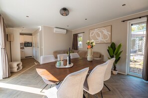 Une salle à manger moderne avec une table en bois, des chaises de couleur beige et un vase rempli de fleurs.