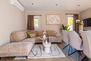 A modern living room with a sectional sofa, a coffee table, and a TV. - Groeneborg Lodge | 6p (Ruinen)