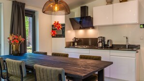Une cuisine moderne avec un coin repas comprenant une table et des chaises, un luminaire suspendu et une statue de Bouddha.