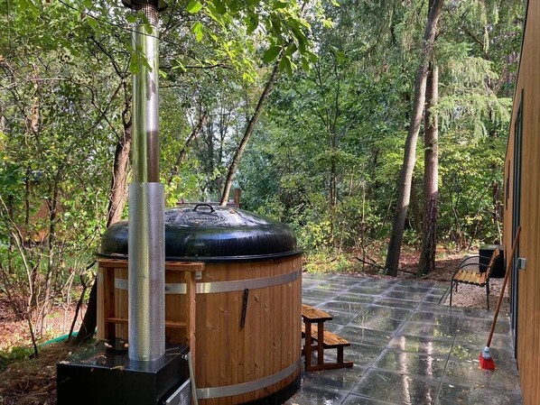 Una sauna con revestimiento de madera, una chimenea de metal y un banco.