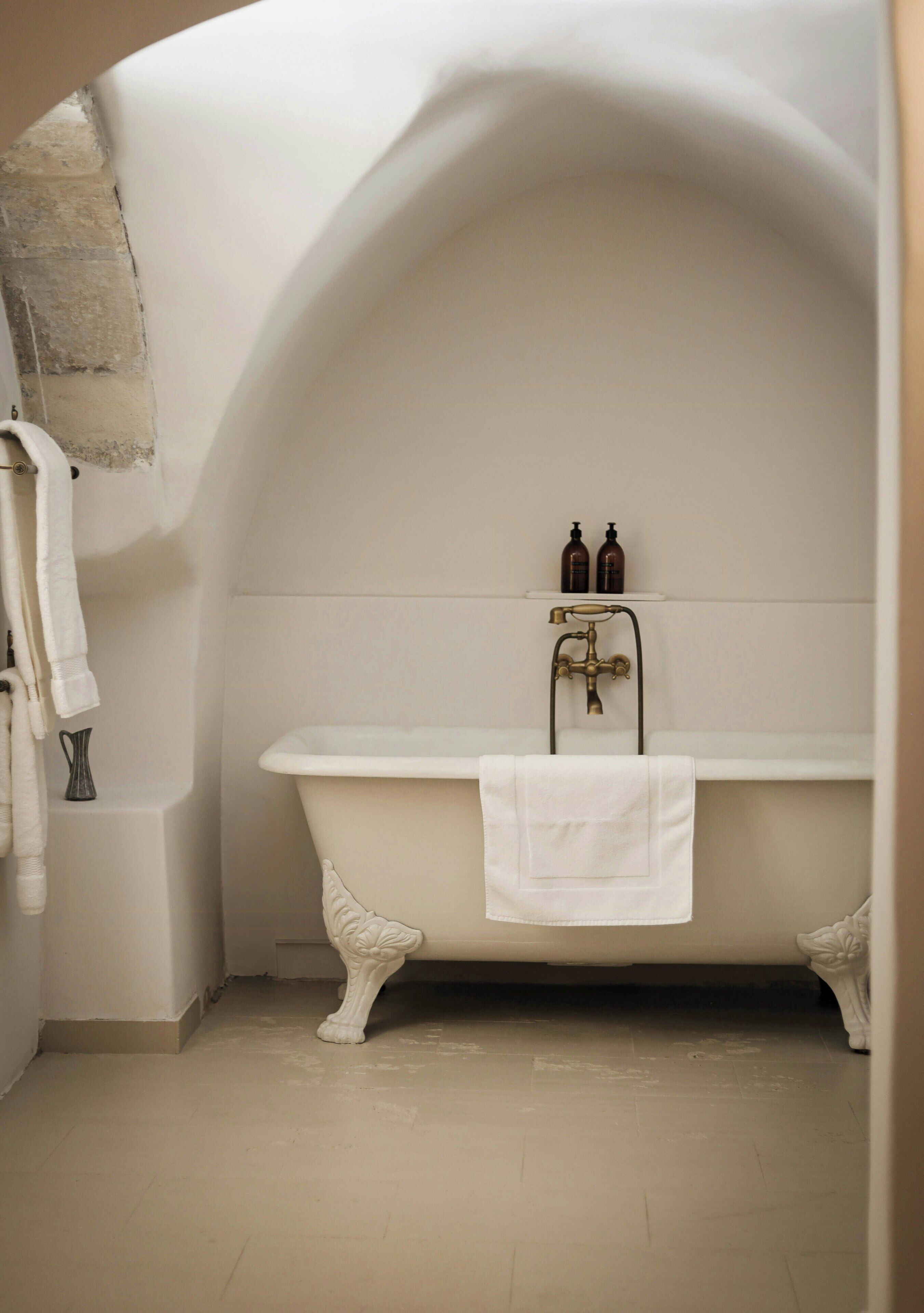 Ein Badezimmer mit einer Badewanne auf Füßen, einem Handtuchhalter und einem Ablagefach mit Toilettenartikeln.