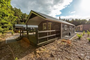 Eine Hütte mit Veranda, überdachter Eingangszone und kleiner Terrasse.