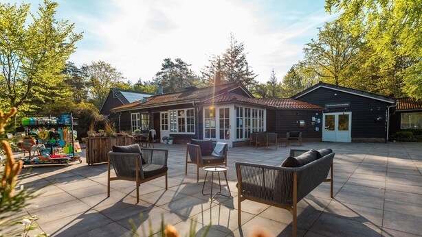 A patio area with outdoor seating, a small building with a tiled roof, and a shop with colorful items. - De Wiltzangh - Veenborg Lodge | 4p (Ruinen)