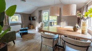 A modern dining area with a wooden table, chairs, pendant lights, and a view of the outdoors. - De Wiltzangh - Veenborg Lodge | 4p (Ruinen)
