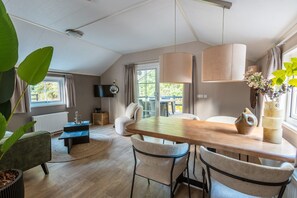 Ein moderner Essbereich mit Holztisch, Stühlen, Pendelleuchten und Blick ins Freie.