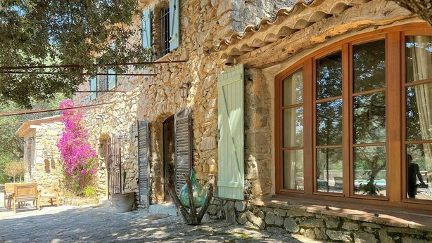 Un bâtiment en pierre avec une fenêtre, une porte et un banc à l’extérieur.
