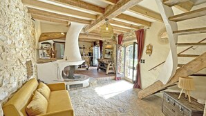 Un intérieur rustique avec un mur en pierre, des poutres en bois, une cheminée en pierre et un escalier.