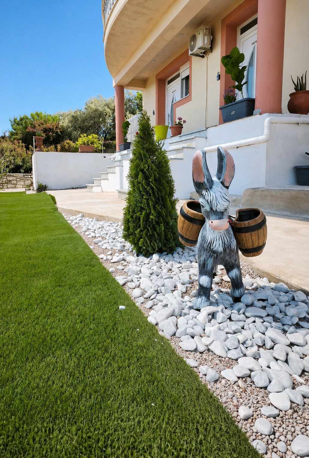 A building with a white facade, a green lawn, and a statue of a donkey.