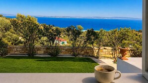 A balcony with a view of the sea, a cup of coffee, and a stone wall. - Nefeli Sea View Stay - Mastiha Grove Suite, Chios (Chios)