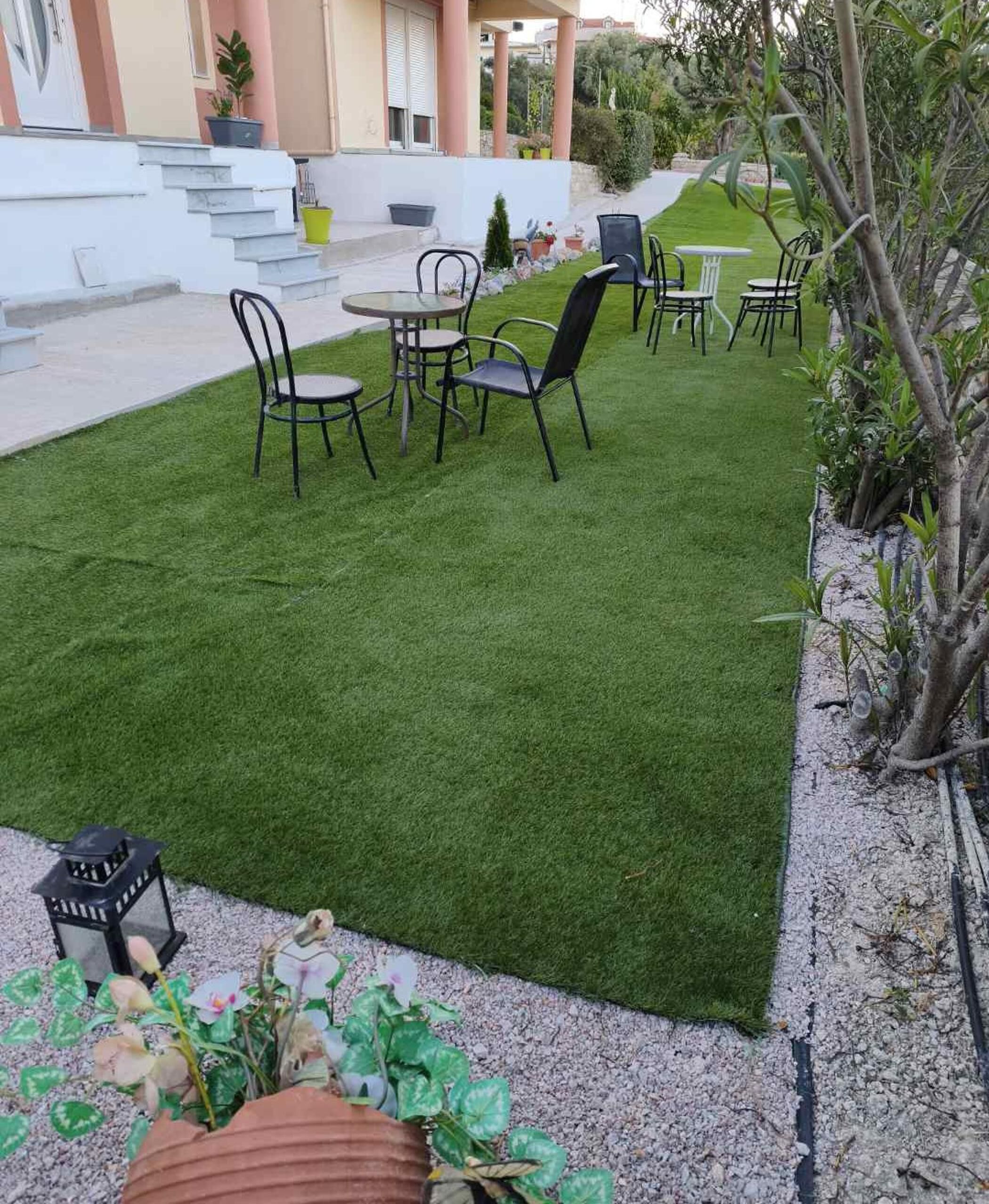 Un'area patio con erba sintetica, mobili da esterno e un piccolo giardino con vasi di piante.