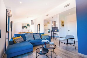 A modern living room with a blue sofa, a dining area, and a kitchen in the background. - Modern villa with sea view in Collioure (Collioure)