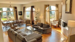 A spacious living room with a dining area, large windows, and a fireplace. - Villa with Pool in Châteauneuf-du-Pape (Chateauneuf-du-Pape)