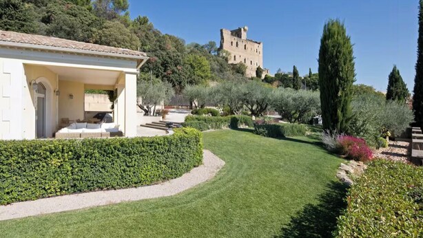 A villa with a garden, a stone building in the background, and a clear sky. - Villa with Pool in Châteauneuf-du-Pape (Chateauneuf-du-Pape)