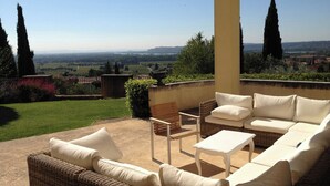 A covered outdoor seating area with wicker furniture and a view of the countryside. - Villa with Pool in Châteauneuf-du-Pape (Chateauneuf-du-Pape)