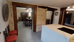 Une cuisine dotée d’un plan de travail en marbre, un coin repas avec une table et des chaises, et un mur en pierre.