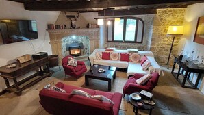 Un salon chaleureux avec une cheminée, des canapés rouges, une table basse et un téléviseur.