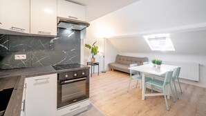 Una cocina moderna con horno integrado, un comedor con mesa y sillas, y una zona de estar acogedora con un sofá.