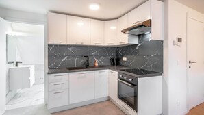 Una cocina moderna con gabinetes blancos, un salpicadero de mármol negro y un horno empotrado.