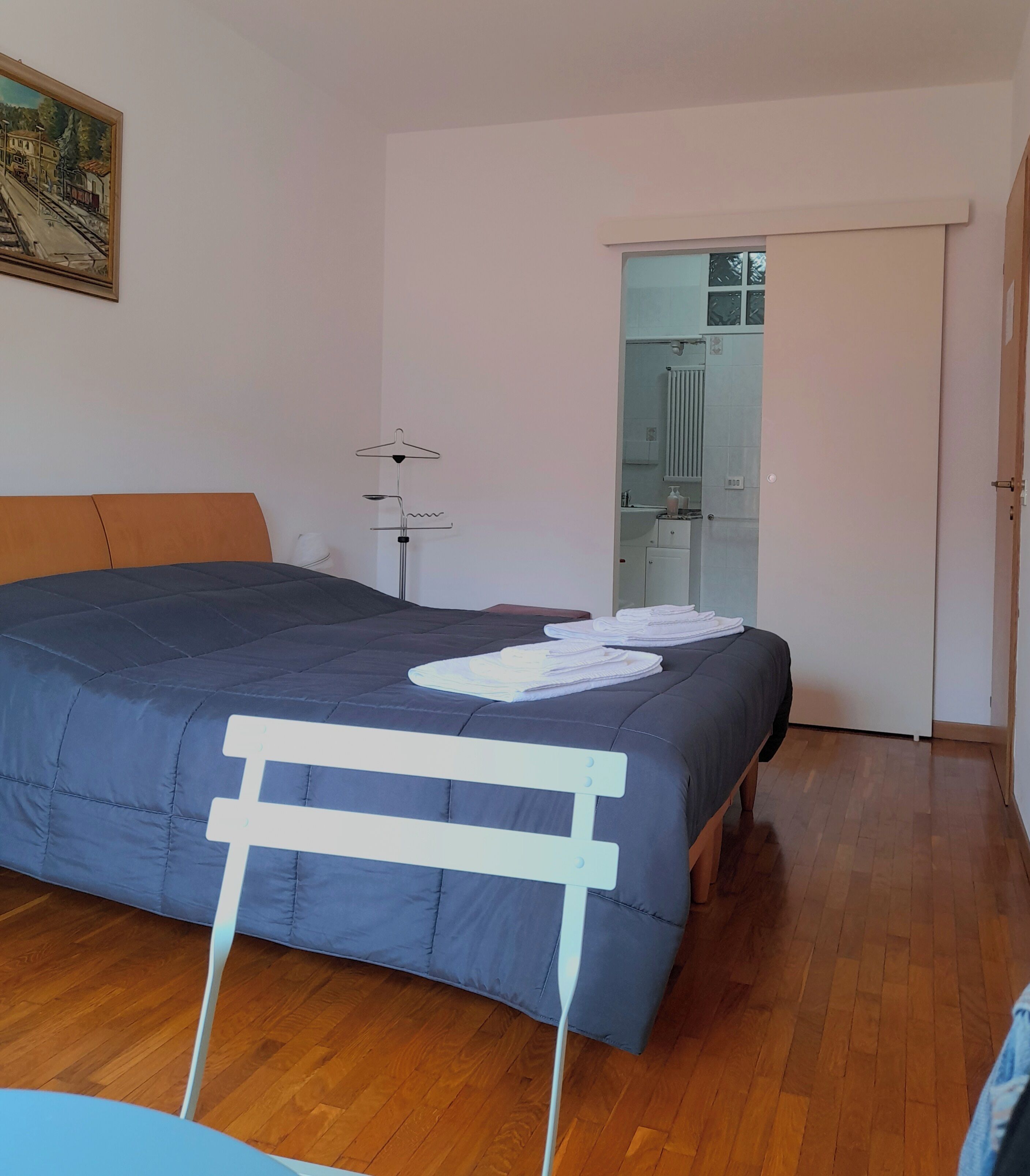Un dormitorio con una cama, una lámpara de pie, un radiador y una puerta que da al baño.