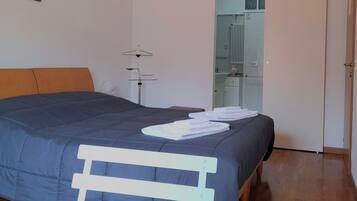 Un dormitorio con una cama, una lámpara de pie, un radiador y una puerta que da al baño.