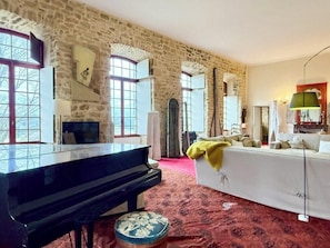 Une pièce avec un piano, un canapé, une lampe et un tapis à motifs.