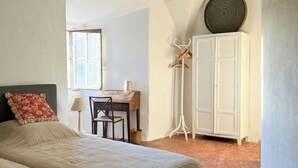 Ein Schlafzimmer mit zwei Betten, einem Schreibtisch, einem Stuhl, einem Kleiderschrank und einer Stehlampe.