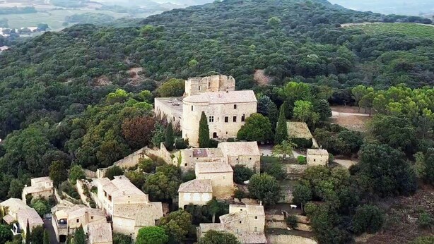 Eine historische Steinburg, umgeben von üppiger Vegetation und terrassierten Feldern.