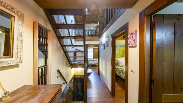 Un escalier en bois mène à une mezzanine où se trouvent un lit et un tableau accroché au mur.