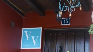 L’entrée d’un hôtel, avec une porte en bois, un panneau néon représentant un lion et une enseigne portant les lettres « VV » et le chiffre « 15 ».