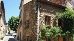 A narrow street with stone buildings, a street lamp, and parked cars. - Villa dans le Golfe de Saint-Tropez (Cogolin)
