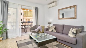 En stue med sofa, sofabord, stol og udsigt til en balkon.