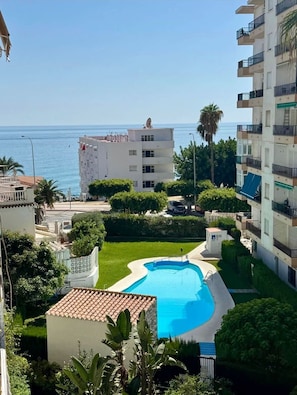 A residential area with a swimming pool, a building with balconies, and a view of the sea. - Nerja Beachfront Apartment Sea Views and Balcony (Nerja)