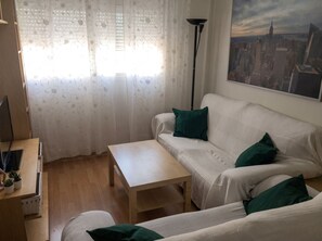Ein Wohnzimmer mit einem weißen Sofa, einem kleinen Tisch und einem Stadtbild an der Wand.