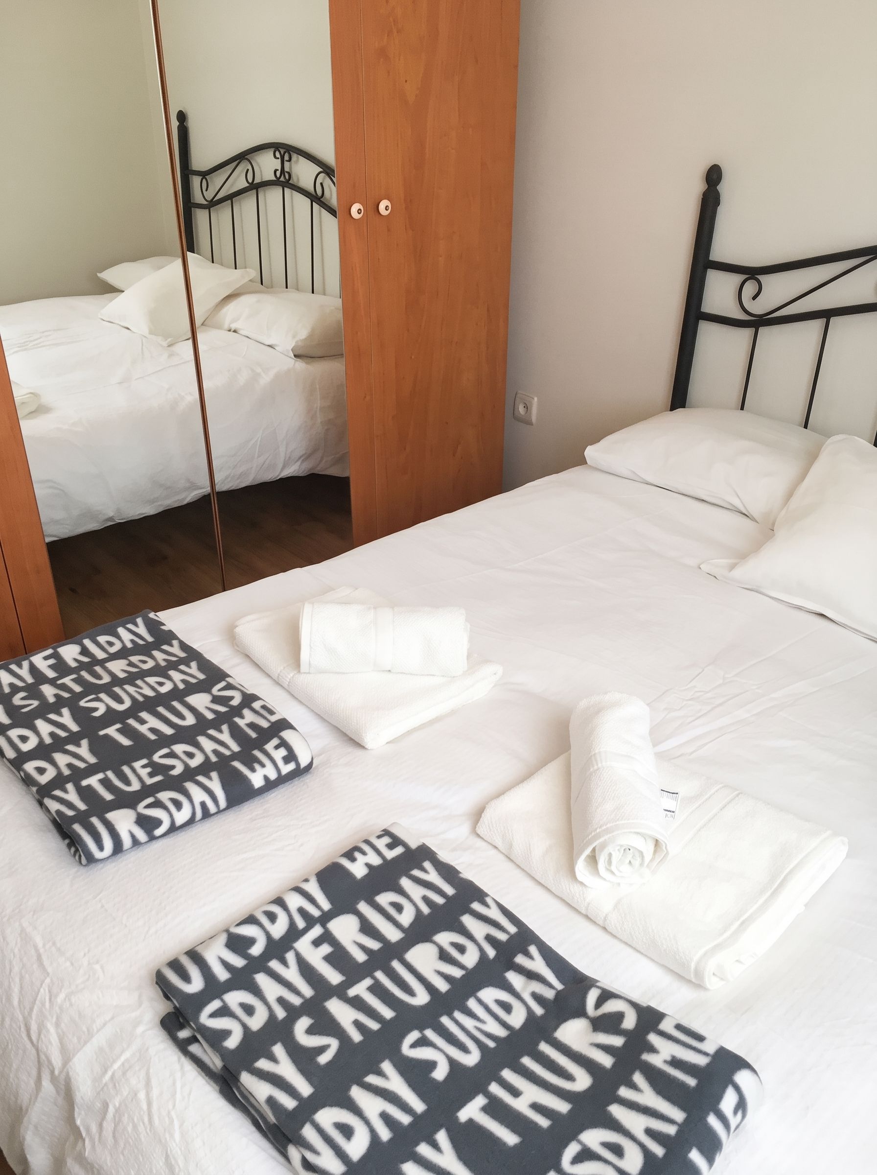 Una cama bien hecha con toallas dobladas y un cartel que indica los días de la semana.