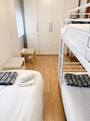 Ein Schlafzimmer mit zwei Betten, einer hölzernen Bank und einem Kleiderschrank.