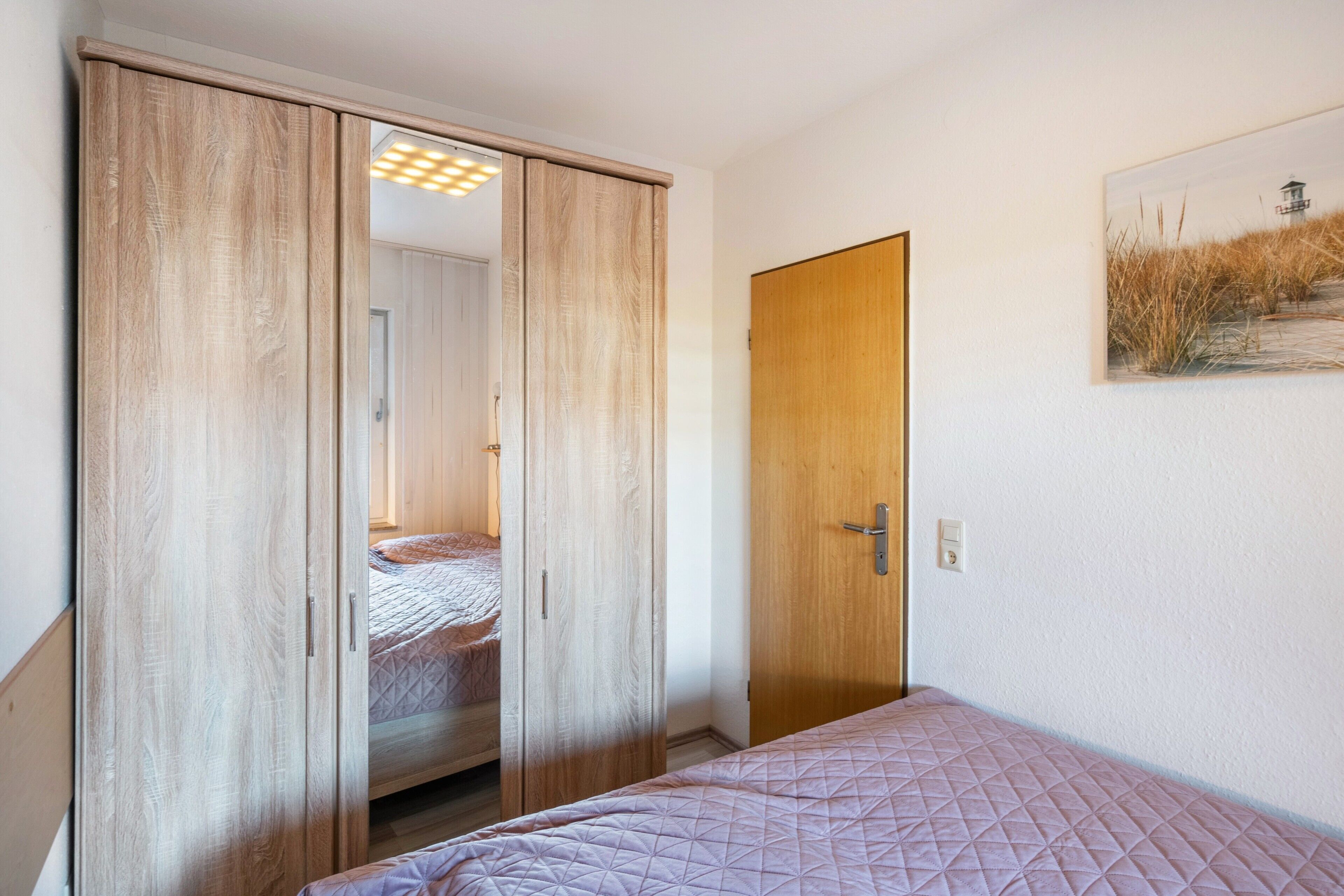 A bedroom with a bed, a wardrobe, and a door.