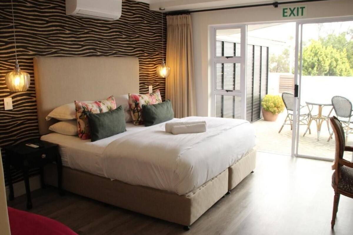 Un dormitorio con cama, mesita de noche y puerta de salida.