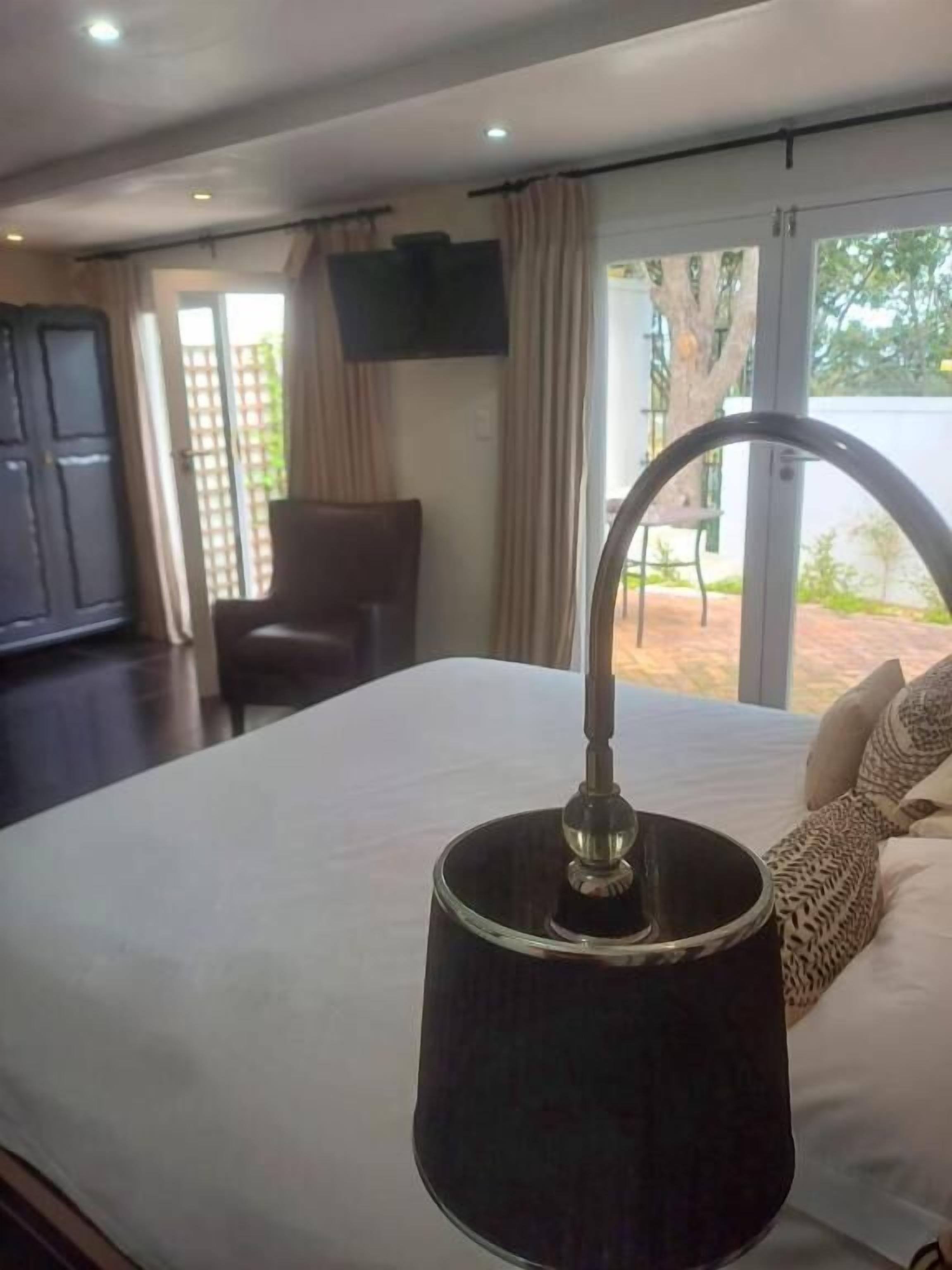 Habitación de hotel con cama, escritorio, silla, televisor y vistas al exterior.