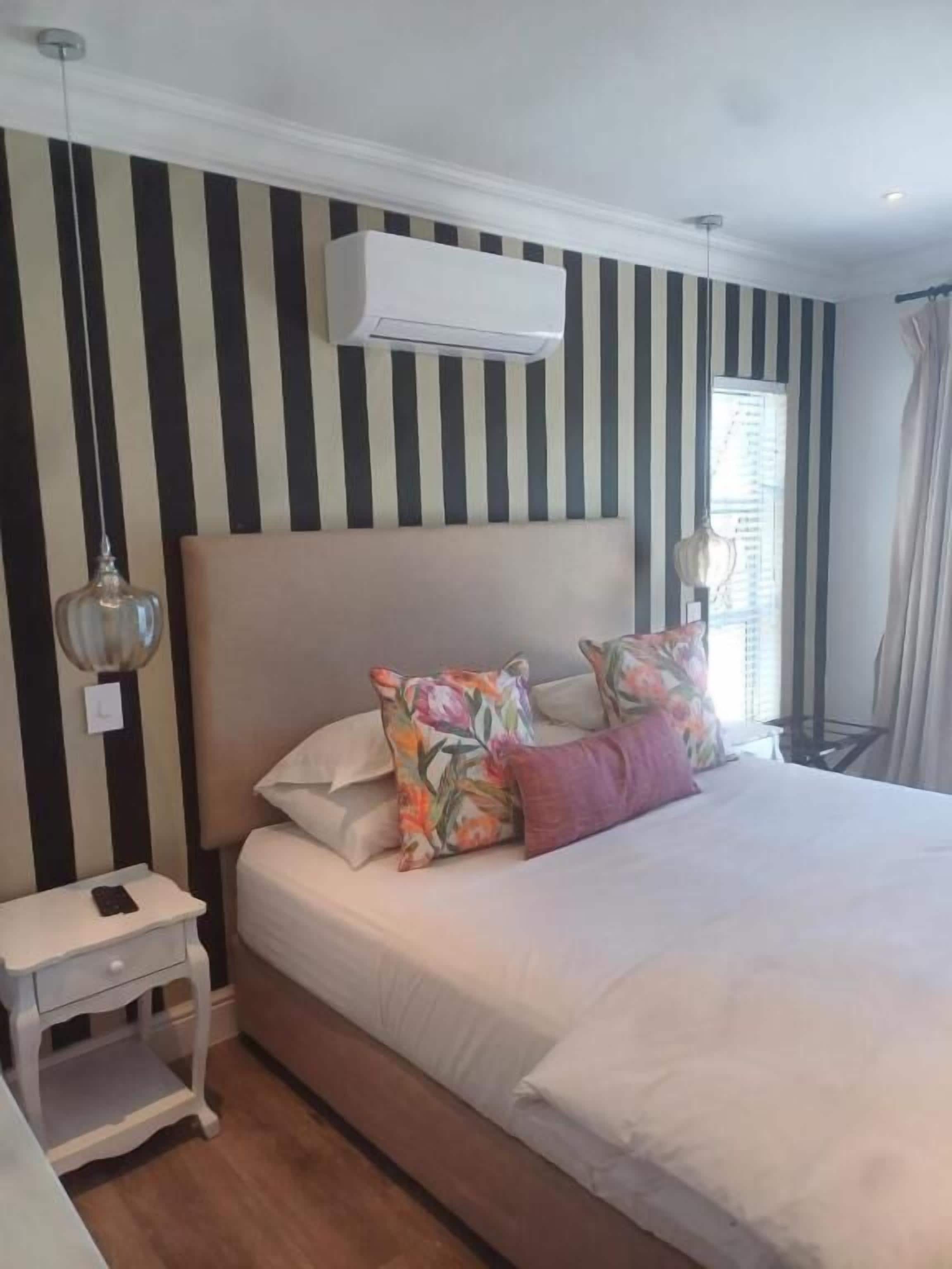 A bedroom with a bed, bedside table, and a window with curtains.